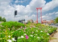 The red Giant Swing is a religious structure in Phra Nakhon with colorful flower garden in cloudy sky day.